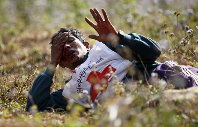 A wounded Red Cross volunteer lies on ground after vehicles of a civilian rescue convoy were attacked by Kokang rebels near the self-administered Kokang capital Laukkai, northern Shan State, Myanmar, February 17, 2015. Two volunteers from the Myanmar Red Cross Society were injured in the convoy attack. Photo: Lynn Bo Bo