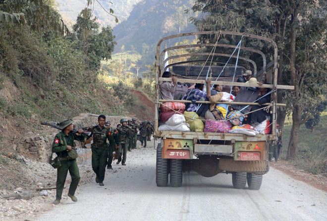A rescue truck loaded with fleeing civilians passes military troops near the Kokang capital Laukkai, northern Shan State, Myanmar, February 17, 2015. Photo: Lynn Bo Bo/EPA