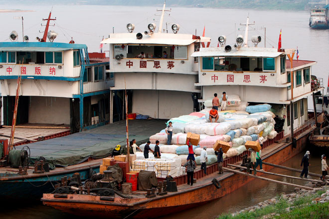 Workers load bags of rubber sheets and cotton onto a Chinese ship in the Thai port of Chiang Saen on the Mekong river, March 29, 2008, in the Golden Triangle region of northern Thailand, where the Mekong river meets at the borders of Laos, Thailand and Myanmar. Photo: Barbara Walton/EPA