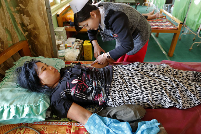 Ma Chaw Chaw (L), 21, a war victim who fled from the conflict zone, gets treatment at a monastery which is being set up as a temporary refugee camp in Lashio, northern Shan State, Myanmar, February 19, 2015. Photo: Lynn Bo Bo/EPA