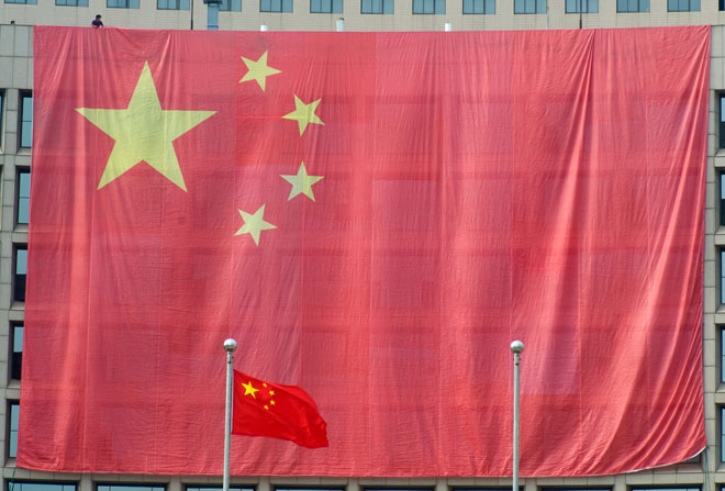 A worker hangs a large Chinese national flag covering a local government building to celebrate the upcoming National Day in downtown Qingdao city, eastern China's Shandong province, September 30, 2011. Photo: Wun Hong/EPA