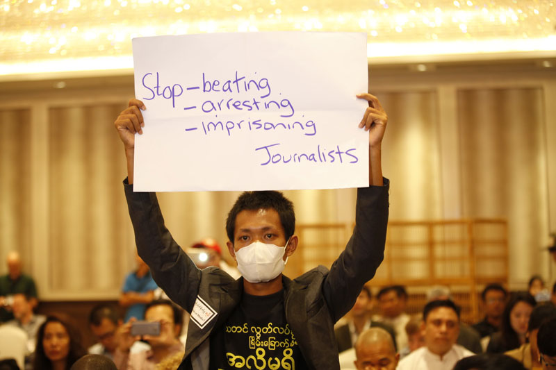 A masked protester holds up a sign in protest while Information Minister U Ye Htut is speaking during the opening session of the IPI World Congress on media freedom in Yangon on March 27, 2015. Photo: Hong Sar/Mizzima