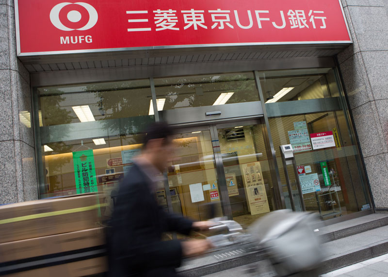 A businessman rides his bike past a Bank of Tokyo-Mitsubishi UFJ branch in Tokyo, Japan, 14 May 2014. Photo: Christopher Jue/EPA