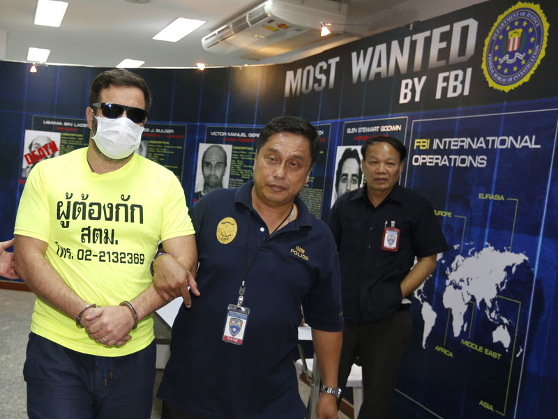Cracking down on drug traffickers - Alleged drug trafficker, French national Jonathan Plant (L), 40, is escorted by police officers for a press conference at the Immigration Bureau in Bangkok, Thailand, July 30, 2014. Photo: EPA