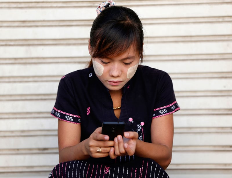 A woman using her smartphone in Pyinmana city near Nay Pyi Taw, Myanmar, November 10, 2014. Photo: Rungroj Yongrit/EPA