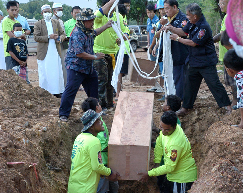 A photo made available on 04 May 2015 shows Thai rescue workers and Muslim villagers burying coffins containing the remains of suspected ethnic Rohingya migrants. Photo: EPA