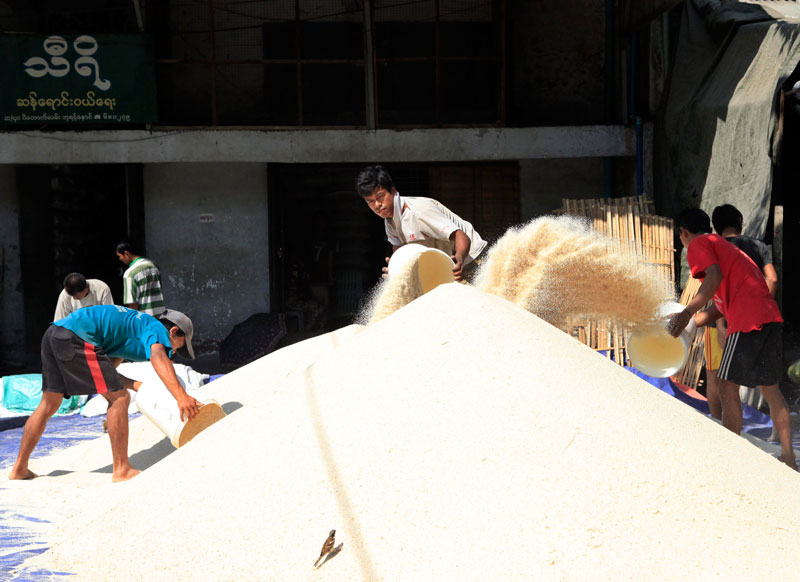 Myanmar workers dry rice under the sun at the Bayintnaung broker's sale centre in Yangon. Photo: Nyein Chan Naing/EPA