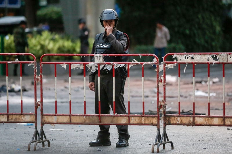 A police officer stands behind a fence as investigative work is done at the scene where a bomb was detonated on 17 August outside Erawan Shrine in central of Bangkok, Thailand, 18 August 2015. Photo: Diego Azubel/EPA