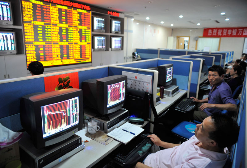 Several investors watch the computer screens showing the stock price information at a securities exchange house in downtown Qingdao city, eastern China's Shandong province. Photo Wu Hong/EPA