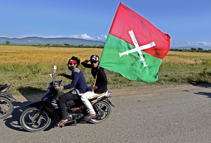 Kachin men saluting and holding the Kachin State flag as they follow a convoy of ethnic leaders in Myitkyina, Kachin State, Myanmar, 02 November 2013. Photo: Nyein Chan Naing/EPA