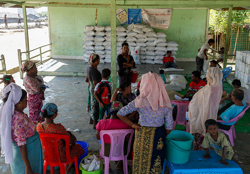 Muslim refugees wait to get their ration as rice bags provided by World Food Program (WFP) piled up to be delivered at Thetkel Pyin Muslim Internally Displaced Persons (IDPs) camp, near Sittwe, Rakhine State, 19 December 2016. Photo: Nyunt Win/EPA