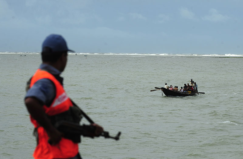 Bangladeshi coast guard watches as a fishing boat passes by in Teknef. Photo: AFP
