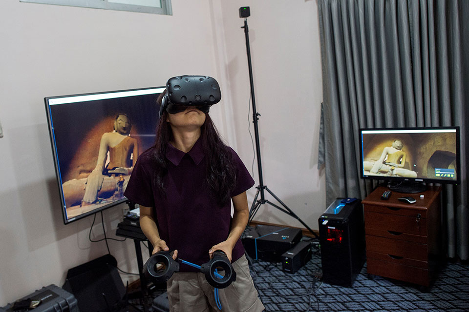In this photograph taken on August 11, 2017, a woman wears VR goggles as she watches some of the 360˚ 4K video footage that a specialized company recorded at the ancient city of Bagan and its crumbling 700-year-old buildings, while visiting the office of Nyi Lin Seck during an open house visual event in Yangon. Few countries in the world have experienced such rapid discovery of technology than Myanmar which has leapfrogged from the analogue to digital era in just a few years. Photo: Ye Aung Thu/AFP