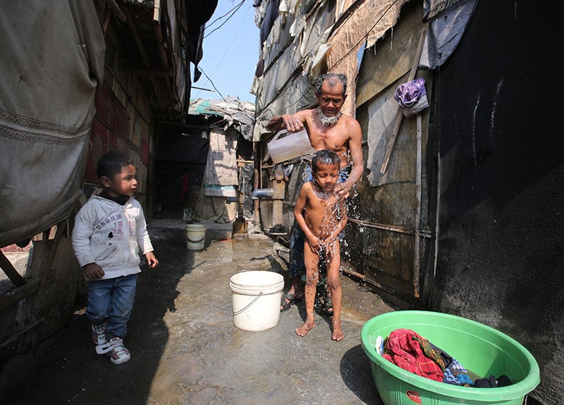 A Rohingya Muslim man and a boy take a wash in a makeshift settlement in Madanpur Khadar in New Delhi, India, 10 February 2017. Photo: Rajat Gupta/EPA