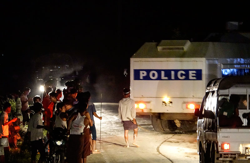 Police vehicles park as people gather around the area near Red Cross boat loaded humanitarian aids dock, Sittwe