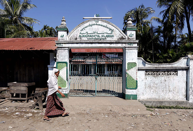 (File) A Muslim woman walks in front of the local mosque in the Aung Mingalar quarter in Sittwe, western Myanmar, 27 October 2012.