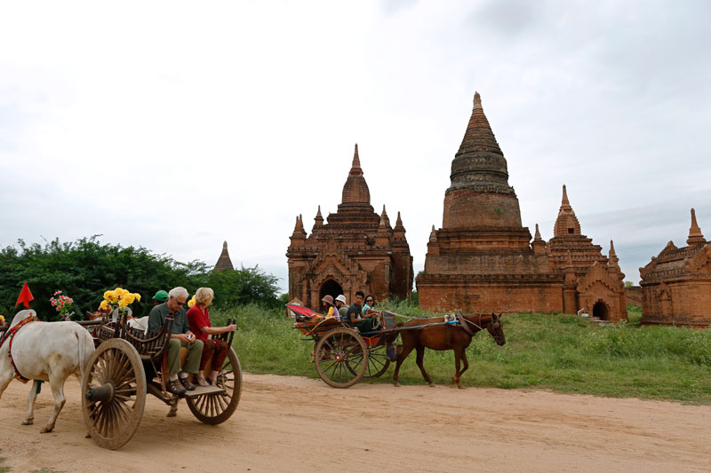 Foreign tourists ride on bullock carts during their sightseeing in Bagan city, Myanmar.