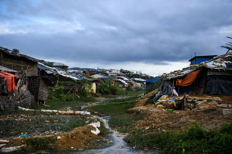 A Rohingya refugee woman (R) works outside her tent at the Kutupalong camp in Ukhia near Cox's Bazar on August 13, 2018. Nearly 700,000 Rohingya fled Myanmar's Rakhine state last year to escape a violent military crackdown. Photo: Chandan Khanna/AFP