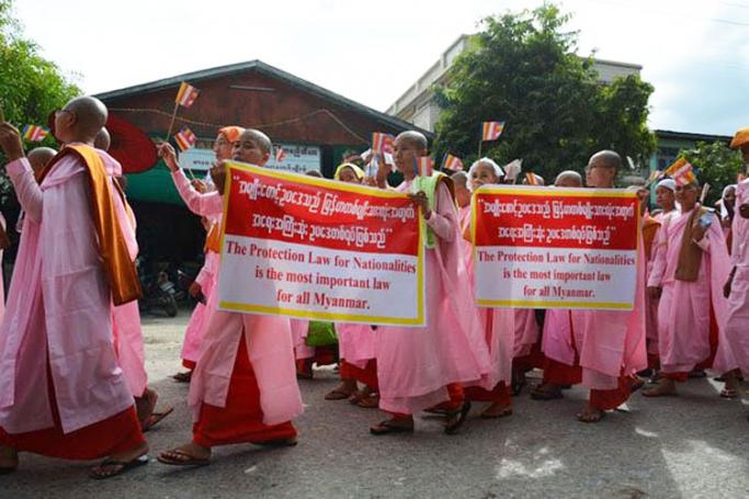 Buddhist nuns hold Buddhist flags as they participate during a demonstration in Mandalay, Myanmar, 30 October 2014. Thousands of people including Buddhist monks and nuns led by the Race and Religion Protection Organisation, locally abbreviated as Ma-Ba-Tha and also known as the 969 group, demonstrated in Mandalay to prescribe the 'Protection Law' or so called the interfaith marriage law. Photo: APHR