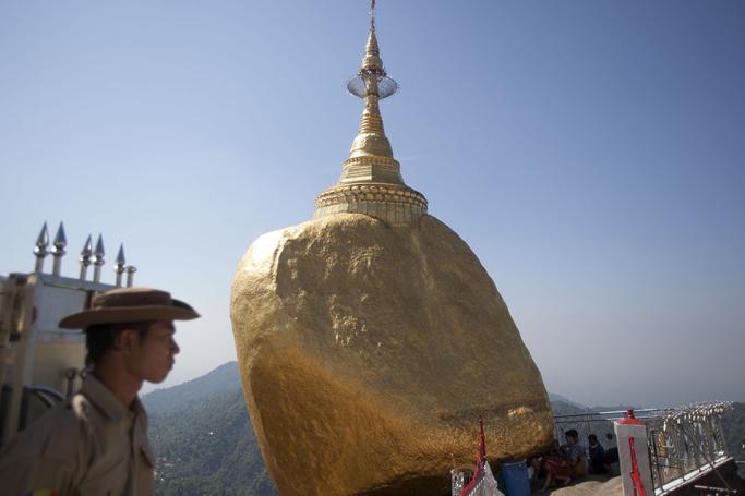 A security guard watches as people pray near the golden Kyite Htee Yoe Pagoda, also known as the Golden Rock, in Mon State, Myanmar. (Photo- EPA/Lynn Bo Bo)