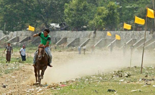 A jockey rides during the horse racing at a pagoda festival at Taungthaman Lake near U Pain Bridge in Amarapura, Mandalay, Myanmar,  March 24, 2015. Photo: Pyae Sone Aung/EPA