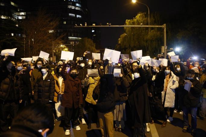 Protesters hold up blank white pieces of paper during a protest triggered by a fire in Urumqi that killed 10 people in Beijing in Beijing, China, 27 November 2022. Photo: EPA