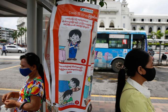  Myanmar women wearing protective face masks stand near a poster promoting health and education about SARS-CoV-2 coronavirus at a bus stop in front of the Yangon City Hall, in Yangon, Myanmar. Photo: EPA