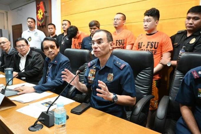Philippines Police Major General Guillermo Eleazar (2nd R) gestures during a press conference with other officials and three (back, orange shirts) of 277 Chinese arrested for "illegal online operations" (AFP Photo/Ted ALJIBE)