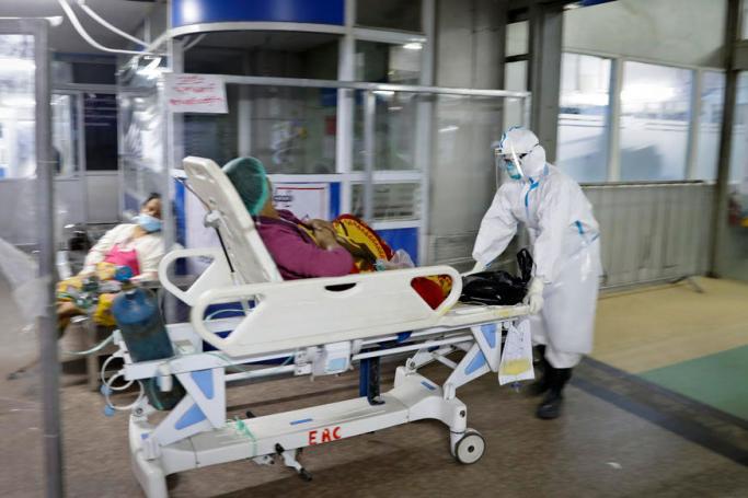 (File) A medical worker wearing PPE (personal protective equipment) moves a patient into COVID-19 cases management zone at the emergency department at Yangon General Hospital, in Yangon, Myanmar, 01 January 2021. Photo: EPA