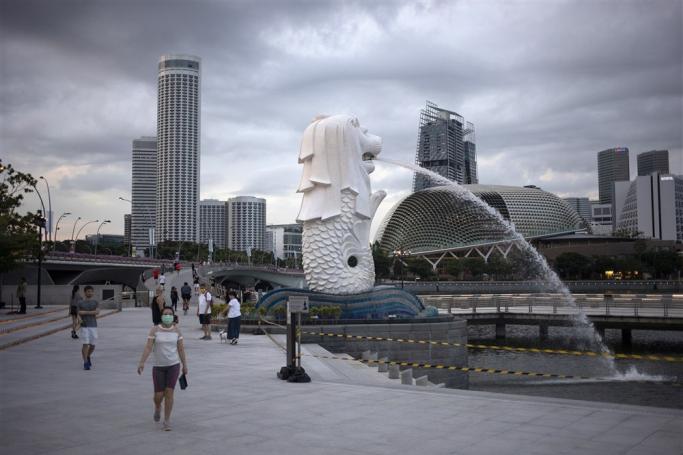 People wearing protective face masks walk in the Merlion Park in Singapore, 11 June 2020. Photo: EPA