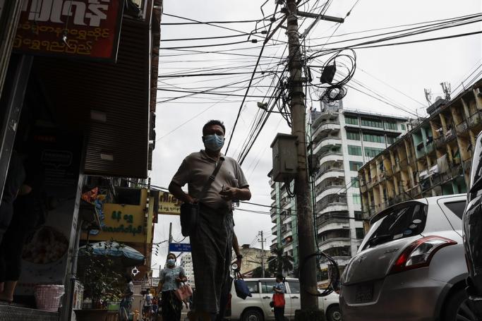Myanmar man passes by electric pole with cables at a roadside at downtown area in Yangon, Myanmar. Photo: EPA
