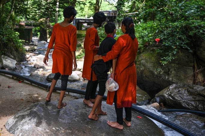 This picture taken on May 30, 2022 shows Loh Siew Hong (R) hugging her son next to her other children by a river in Gombak, Malaysia's Selangor state. Malaysian woman Loh Siew Hong says her husband brutally abused her, battering her over the head and breaking her ankle, before running off with their children and converting them to Islam. Photo: Mohd RASFAN/AFP
