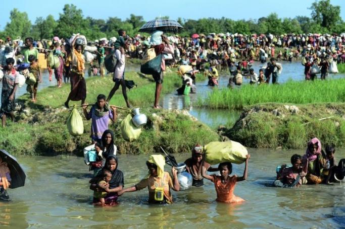 (FILES) In this file photo taken on October 16, 2017, Rohingya refugees walk through a shallow canal after crossing the Naf River in Palongkhali near Ukhia, as they flee violence in Myanmar to reach Bangladesh. Photo: AFP