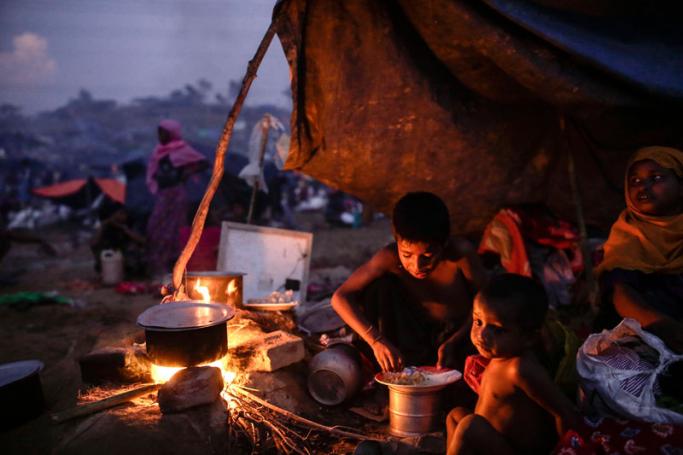 Two Rohingya children eat food at their makeshift tent at Tangkhali, Ukhiya, Bangladesh, 16 September 2017. Photo: Abir Abdullah/EPA-EFE
