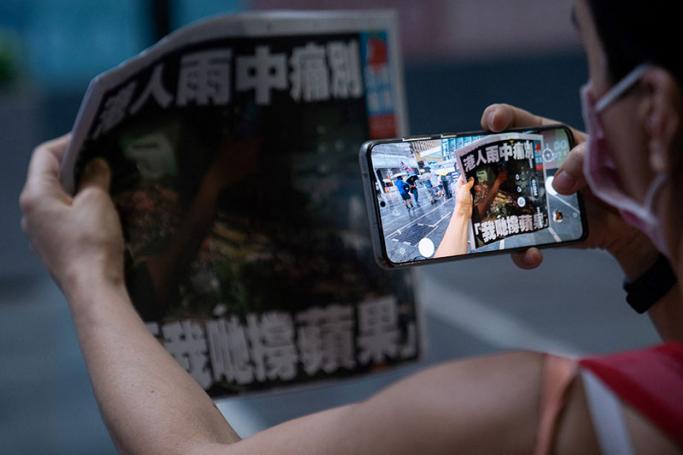 This file photo taken on June 24, 2021 shows a woman taking a photo of the Apple Daily newspaper's final edition in Hong Kong after the pro-democracy tabloid was forced to close after 26 years under a sweeping new national security law. Photo: AFP