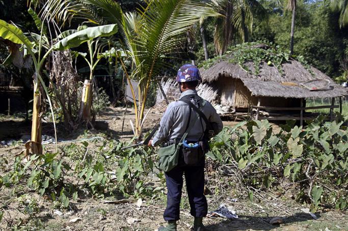 An armed policeman stands guard at the Chain Khar Le village during the visit of Yanghee Lee (not in picture), the United Nations Special Rapporteur on the situation of human rights in Myanmar, Rathedaung town, Rakhine State, western Myanmar, 14 January 2017. Photo: Nyunt Win/EPA
