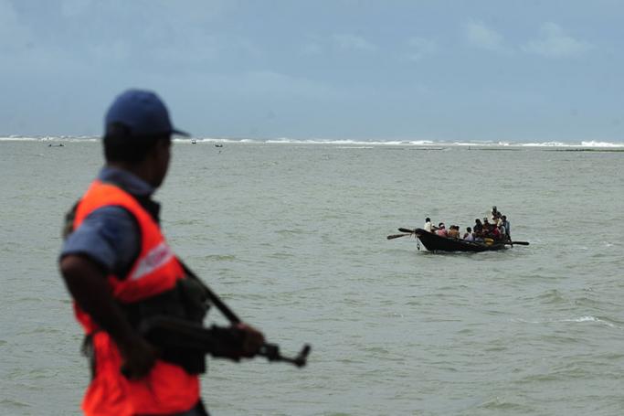 Bangladeshi coast guard watches as a fishing boat passes by in Teknef. Photo: AFP
