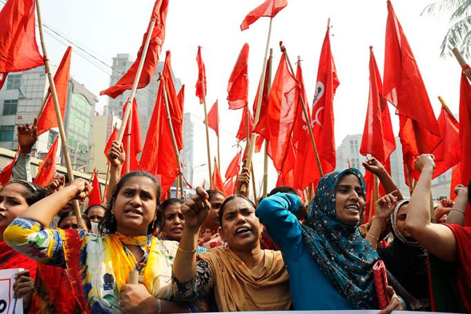 Garment workers shout slogans as they attend a protest rally with red flags demanding the release of 25 of their leaders and reopen the closed factories organised by the National Garment Workers Federation (NGWF) in front of the National Press Club in Dhaka, Bangladesh, 10 February 2017. Photo: Abir Abdullah/EPA
