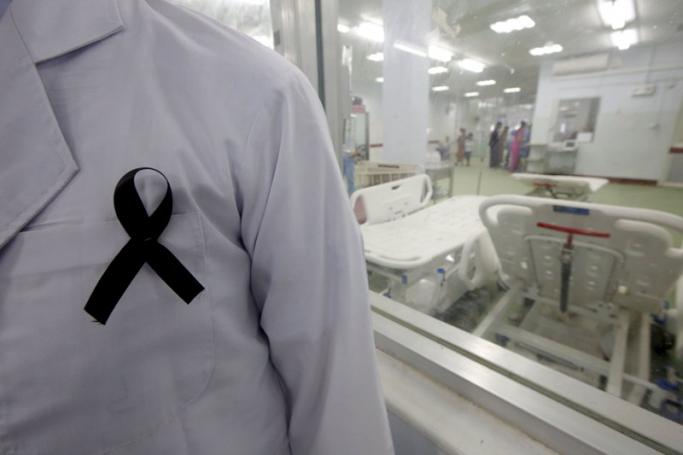 An orthopedic surgeon (L, partially obscured) wears a black ribbon on his medical smock, sympathizing with the 'Black Ribbon Movement', inside an operation theatre at Yangon General Hospital, in Yangon, Myanmar, 11 August 2015. Lynn Bo Bo/EPA
