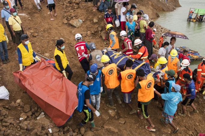 This photograph taken on July 26, 2018, shows search and rescue volunteers carrying the body of a miner after a landslide at a jade mining area in Hpakant, in Myanmar's Kachin state.
