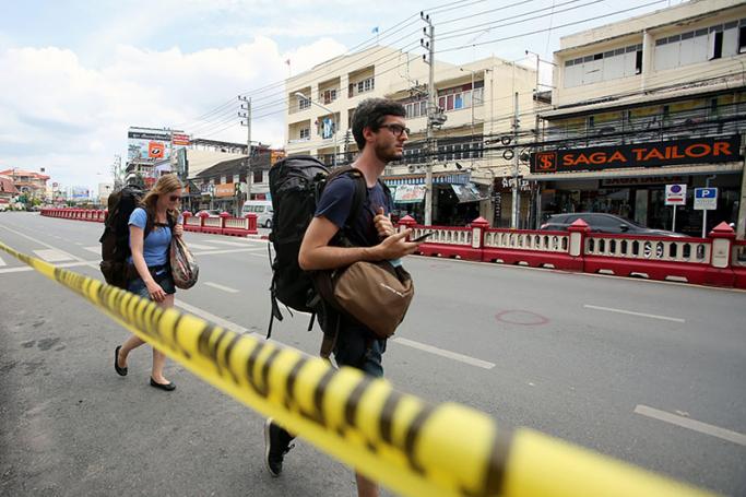 A photo made available on 13 August 2016 shows foreign tourists walking past a police line at the bomb blast site in Hua Hin, Thailand, 12 August 2016. Photo: EPA
