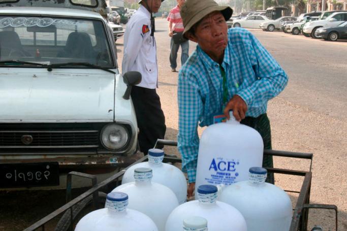 A Myanmar man lifts his bottled drinking water from a cart in Yangon. Photo: Nyein Chan Naing/EPA
