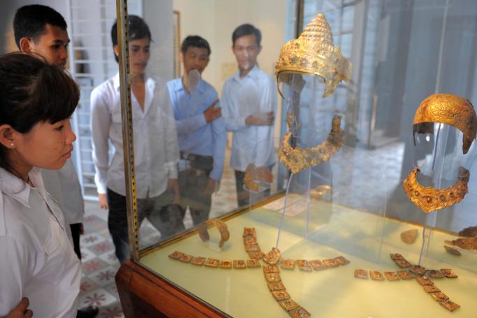 (File) Cambodian students look at the gold and rock crystal Royal Regalia of the Angkor period, 12th and 13th centuries, that is displayed at the National Museum in Phnom Penh on May 26, 2009. Photo: AFP