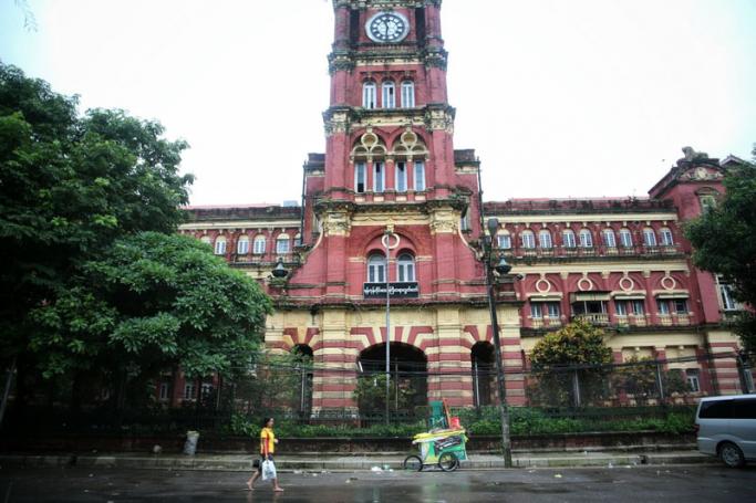 A woman walks past the towering British colonial-era High Court located in downtown Yangon. (Credit: Hkun Lat/Myanmar Now) 
