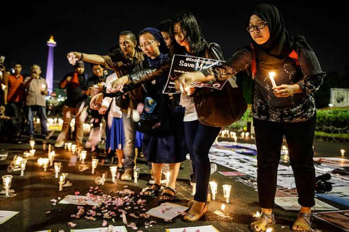Indonesian activists throw flower petals during a candlelight protest against death penalty executions, outside the presidential palace in Jakarta, Indonesia, 28 July 2016. Photo: EPA
