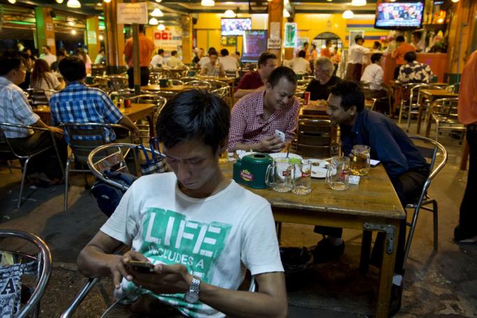 Customers check social media sites from their mobile phone. Photo: AFP
