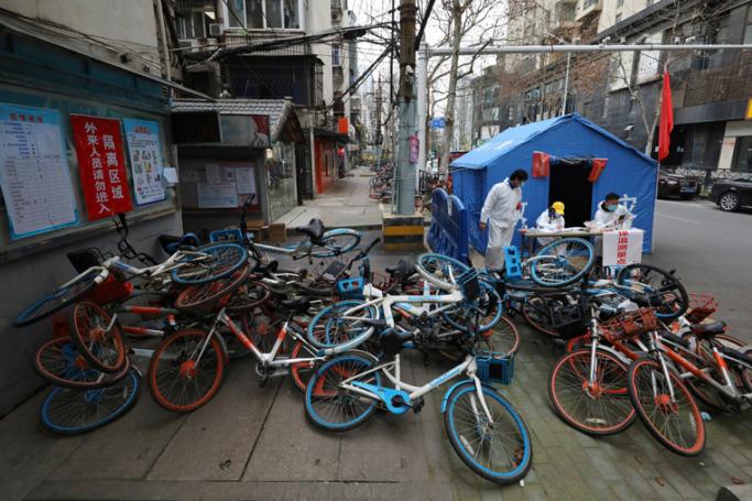 This photo taken on March 16, 2020 shows a pile of shared bicycles set up as a makeshift barrier beside a temperature checking station at the entrance of a residential community in Wuhan, in China's central Hubei province. Photo: AFP