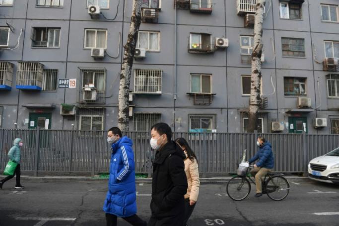 Beijing residents, wearing face masks, walk past a residential building -- the new-coronavirus death toll exceeds that of the 774 killed worldwide by SARS (AFP PHOTO)
