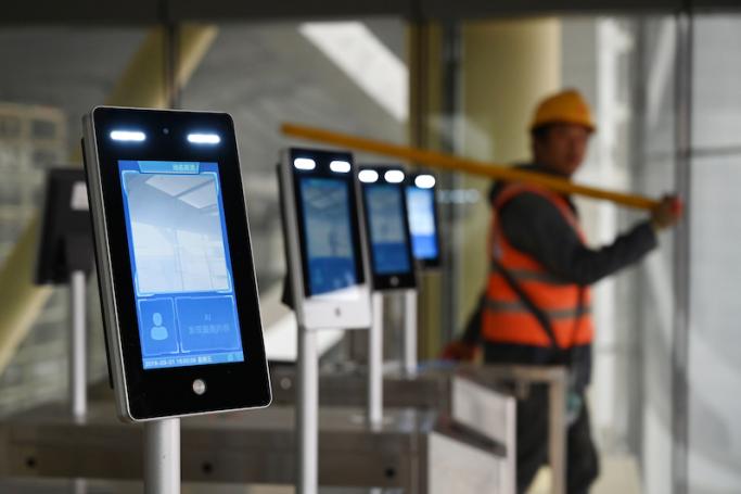 A construction worker walks past facial recognition screens at the entrance to the terminal building of the new Beijing Daxing International Airport, in Beijing. Photo: AFP