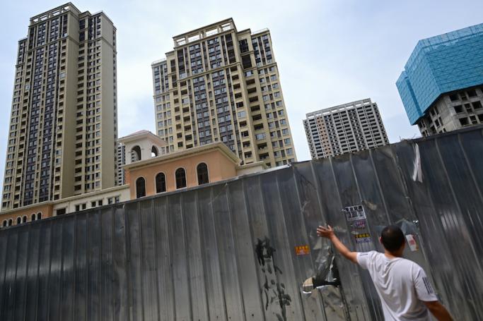 This photo taken on June 20, 2023 shows a man standing by a barrier at a complex of unfinished apartment buildings in Xinzheng City in Zhengzhou, China's central Henan province. Photo: AFP